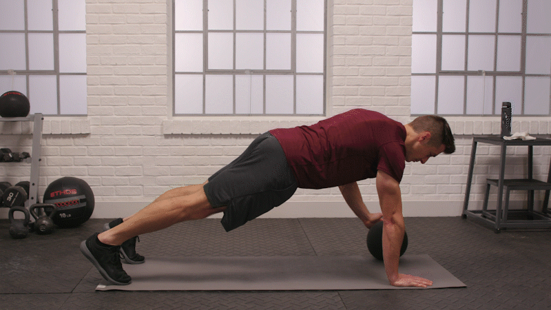 10. Man is doing  Medicine Ball Shoulder Tap Plank